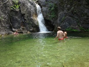 badende Menschen im See vor einem Wasserfall